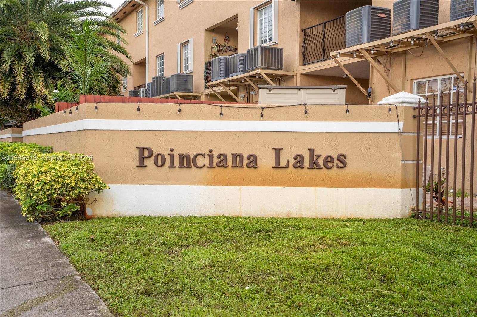 A beige wall with the text Poinciana Lakes stands in front of a multi-story building — 17425 NW 75th Pl # 101, Hialeah FL 33015, HIALEAH, FL