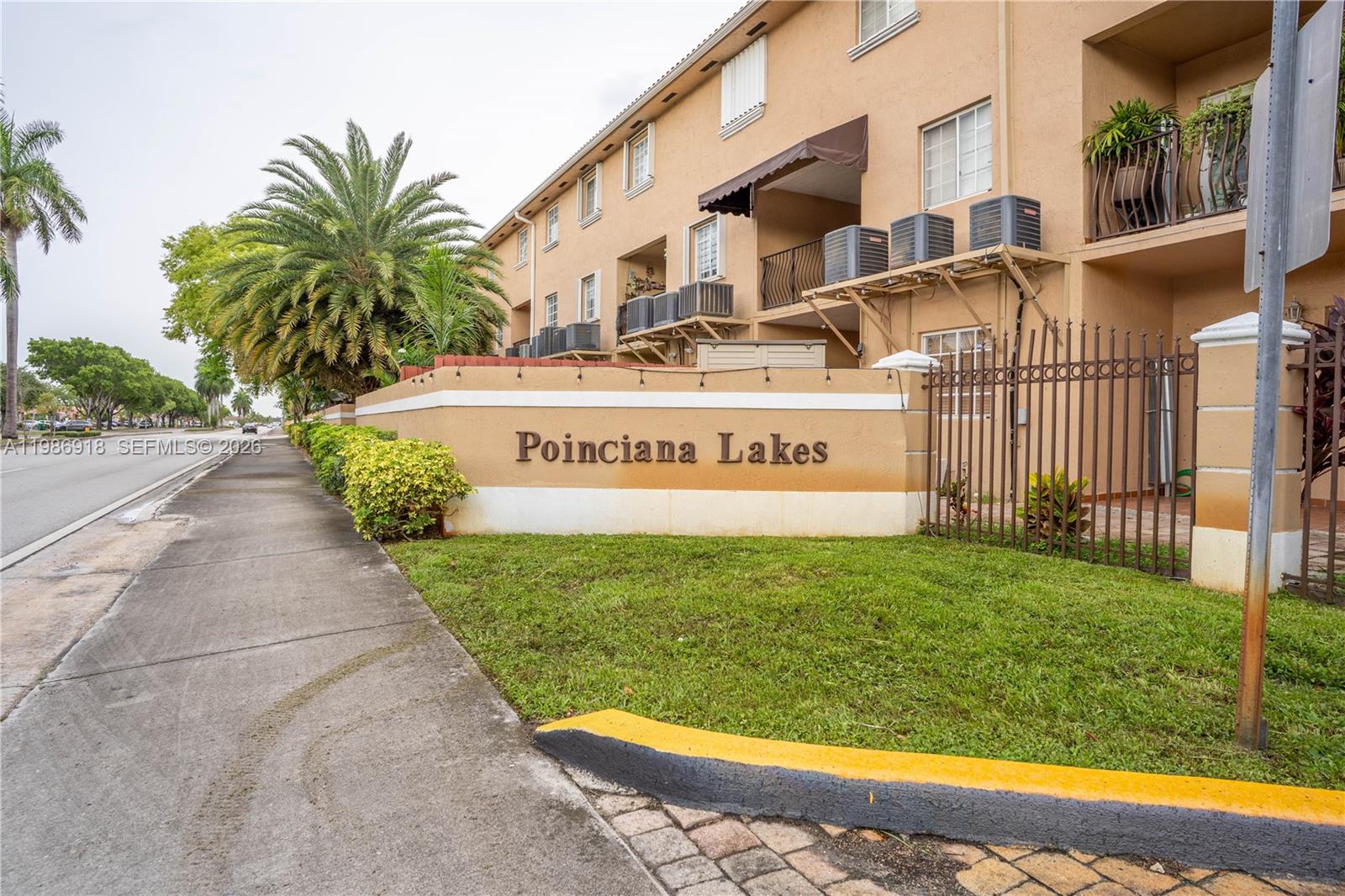 A view of the exterior of the Poinciana Lakes apartment complex from the sidewalk — 17425 NW 75th Pl # 101, Hialeah FL 33015, HIALEAH, FL