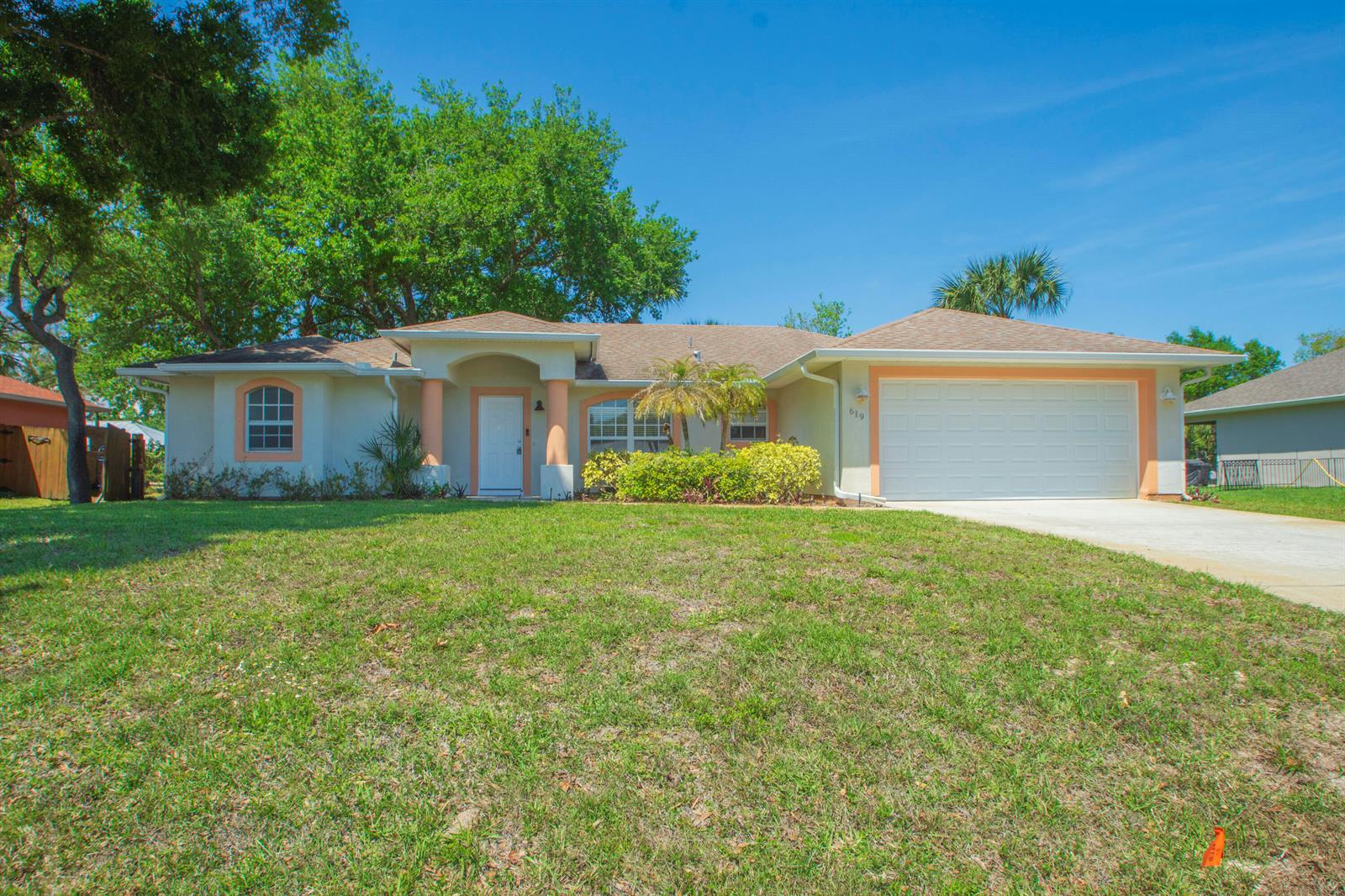 A single-story house with a white garage, arched entryway, and a large front lawn — 619 Carnival Terrace, Sebastian FL 32958, SEBASTIAN, FL