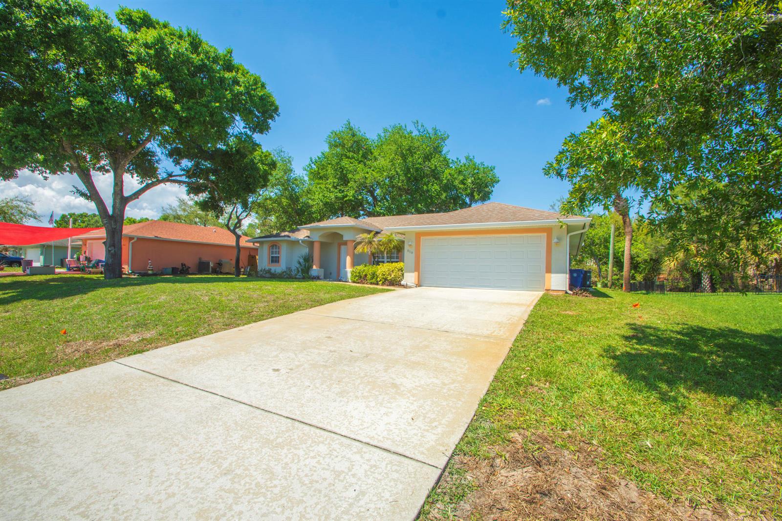 A single-story house with a white garage and a concrete driveway under a blue sky — 619 Carnival Terrace, Sebastian FL 32958, SEBASTIAN, FL