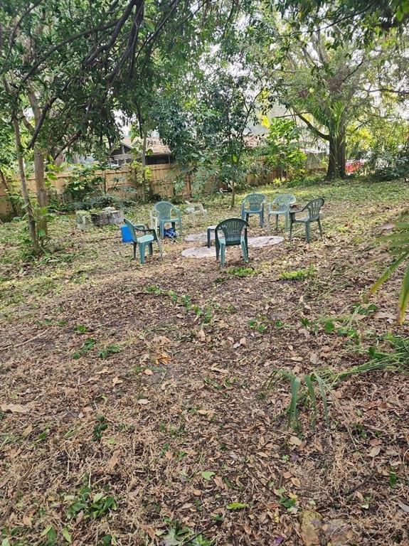 A backyard area features several plastic chairs arranged on a patch of grass and leaves — 2720 BAYSIDE DRIVE S, ST PETERSBURG, FL
