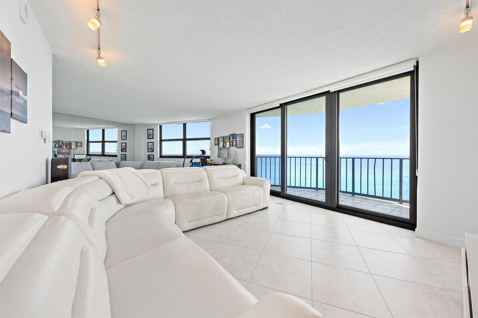 A white sectional sofa sits in a living room with tile floors and ocean views — 5420 N Ocean Drive, Riviera Beach FL 33404, RIVIERA BEACH, FL