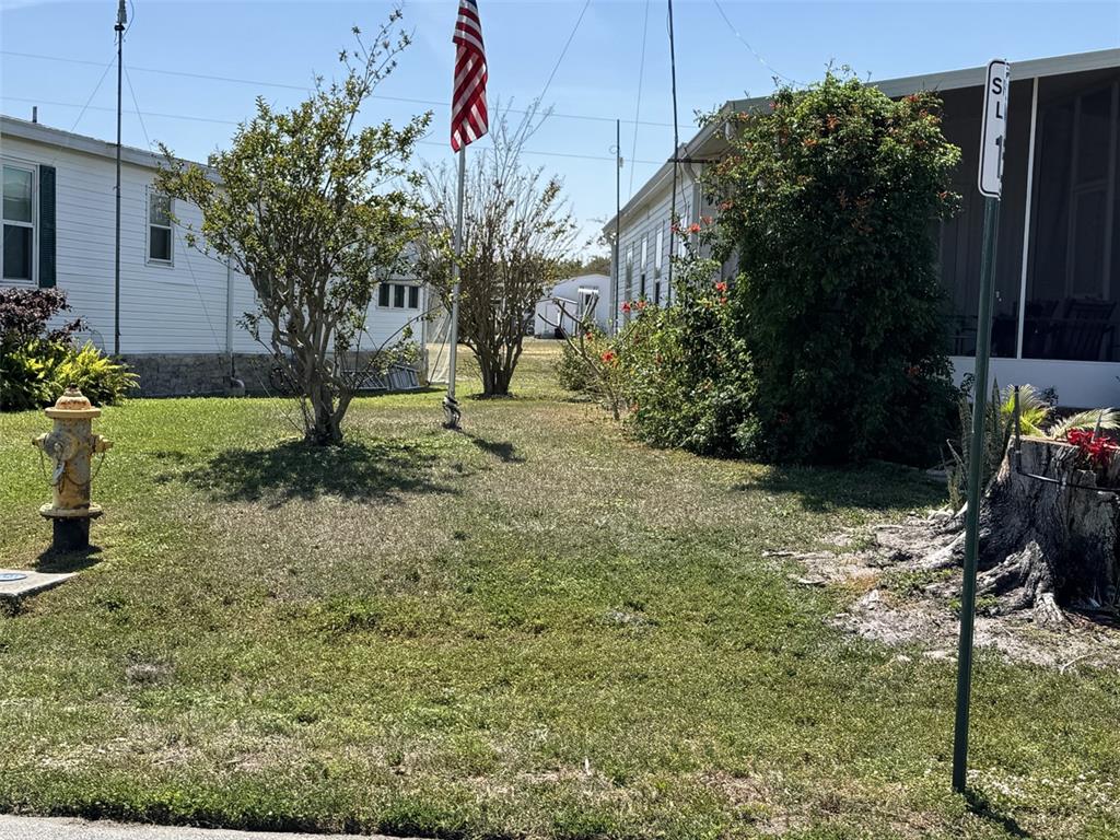A grassy yard features a fire hydrant, an American flag, and two mobile homes — 8689 BREEZE HILL DRIVE, LAKE WALES, FL