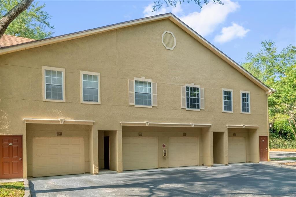 A tan two-story building features multiple garage doors and residential entryways on the ground level — 845 GRAND REGENCY POINT UNIT 203, ALTAMONTE SPRINGS, FL