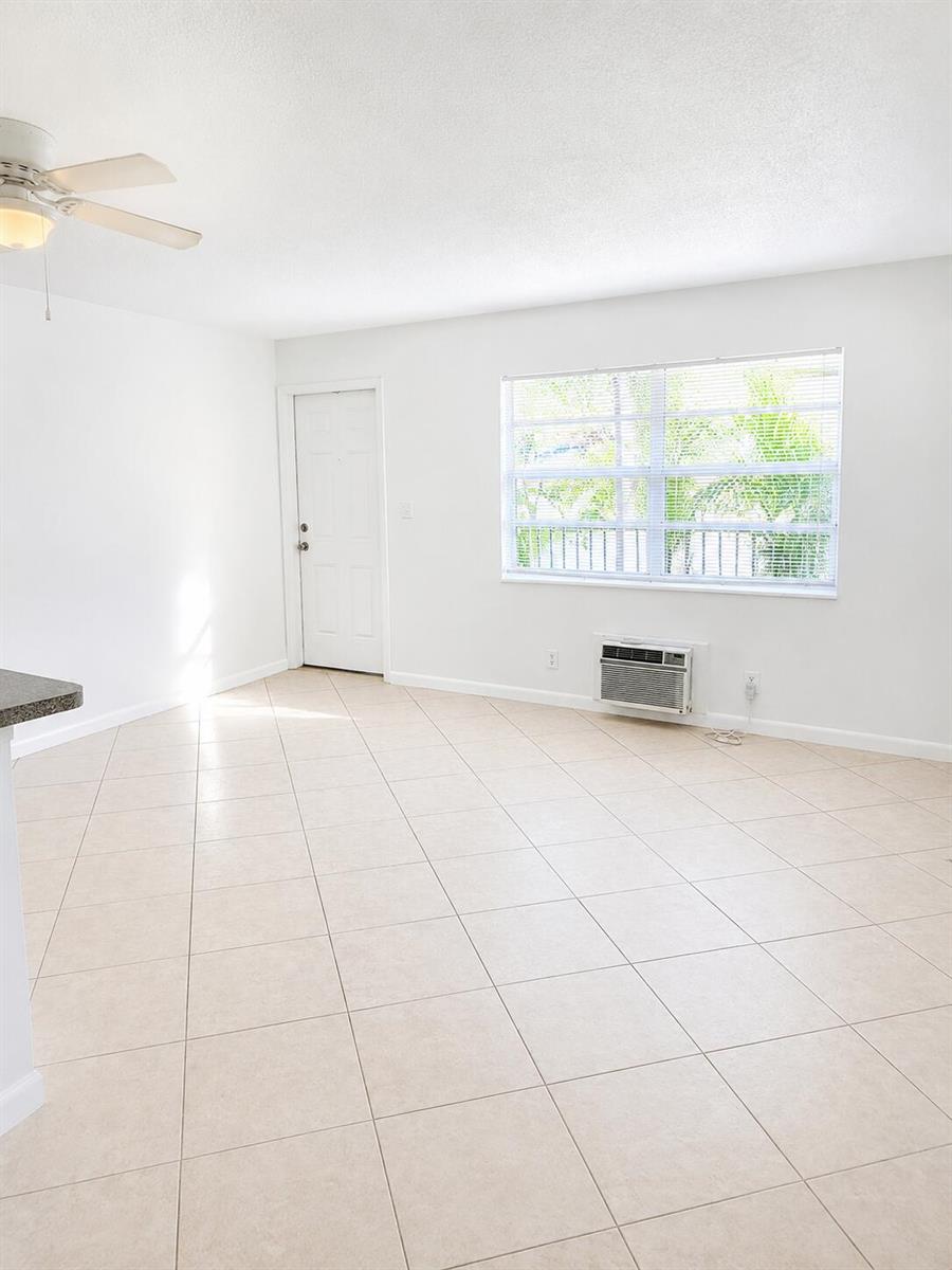 A bright room with white walls, tile flooring, a ceiling fan, and a window unit — 1960 NE 48th Street # 7, Pompano Beach FL 33064, POMPANO BEACH, FL