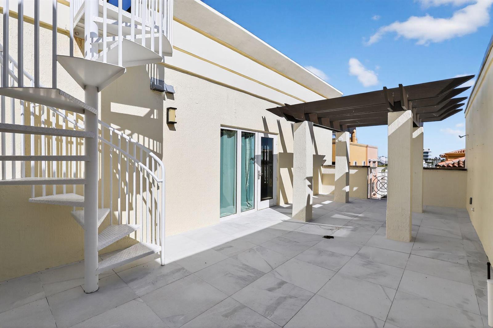 A rooftop terrace features a white spiral staircase, a wooden pergola, and light-colored tile flooring — 120 Jefferson Avenue, Miami Beach FL 33139, MIAMI BEACH, FL