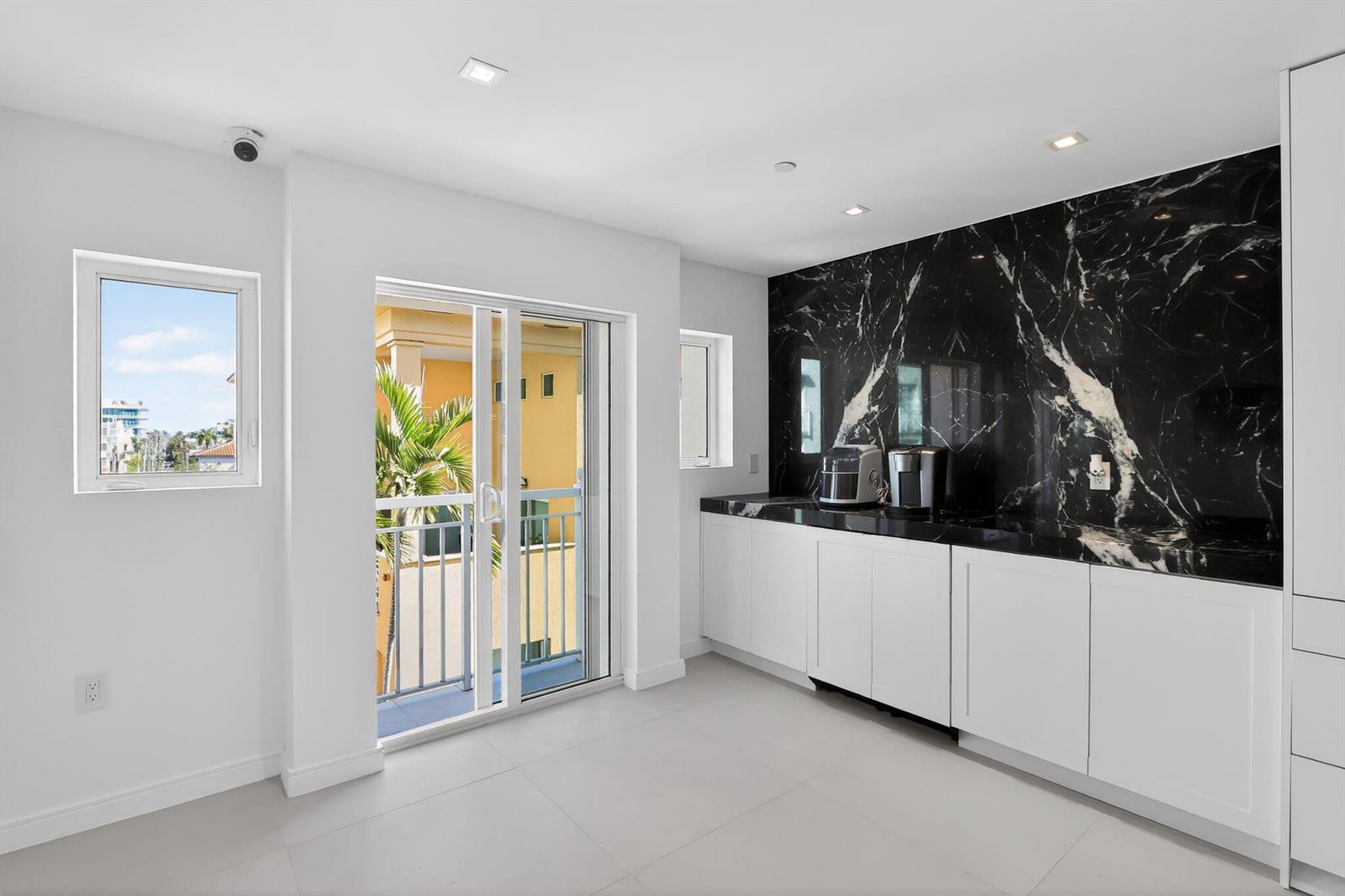 A kitchen area features white cabinets, a black marble backsplash, and a sliding glass door — 120 Jefferson Avenue, Miami Beach FL 33139, MIAMI BEACH, FL