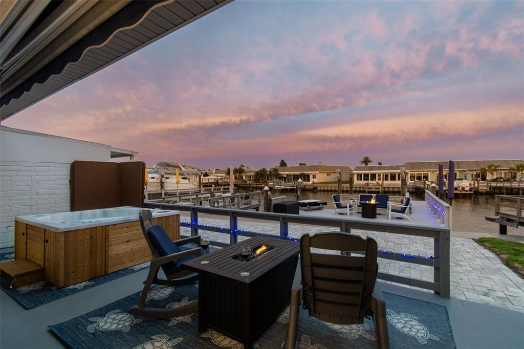 A patio with a hot tub, fire pit, and seating overlooking a canal at sunset — 392 BOCA CIEGA POINT BOULEVARD N, ST PETERSBURG, FL