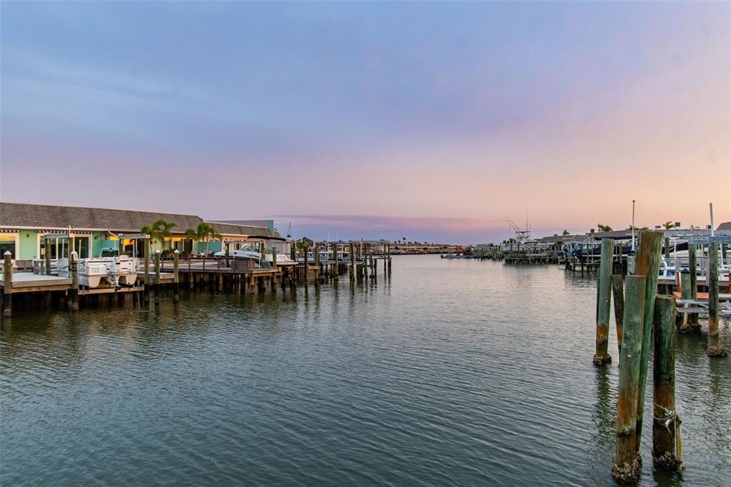 A waterfront view of a canal lined with boat docks and residential buildings at sunset — 392 BOCA CIEGA POINT BOULEVARD N, ST PETERSBURG, FL
