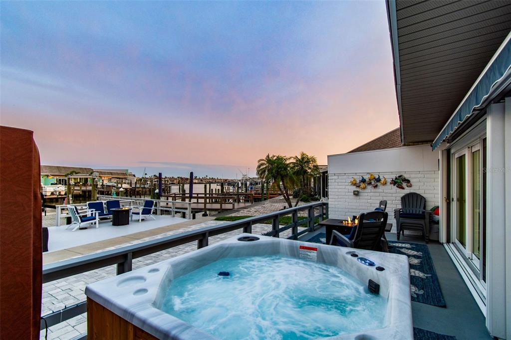 A hot tub sits on a patio overlooking a canal with boats at sunset — 392 BOCA CIEGA POINT BOULEVARD N, ST PETERSBURG, FL