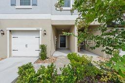 A two-story townhouse exterior with a white garage door and a recessed front entrance — 9177 BONITA MAR DRIVE, PARRISH, FL