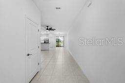 A hallway with white walls and tile flooring leads toward an open-concept kitchen and living area — 9177 BONITA MAR DRIVE, PARRISH, FL