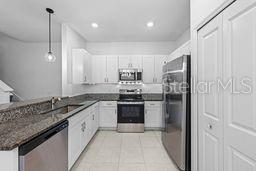 A kitchen features white cabinetry, granite countertops, stainless steel appliances, and a hanging pendant light — 9177 BONITA MAR DRIVE, PARRISH, FL