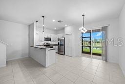 A modern kitchen with white cabinets, stainless steel appliances, and a breakfast bar overlooks a patio — 9177 BONITA MAR DRIVE, PARRISH, FL