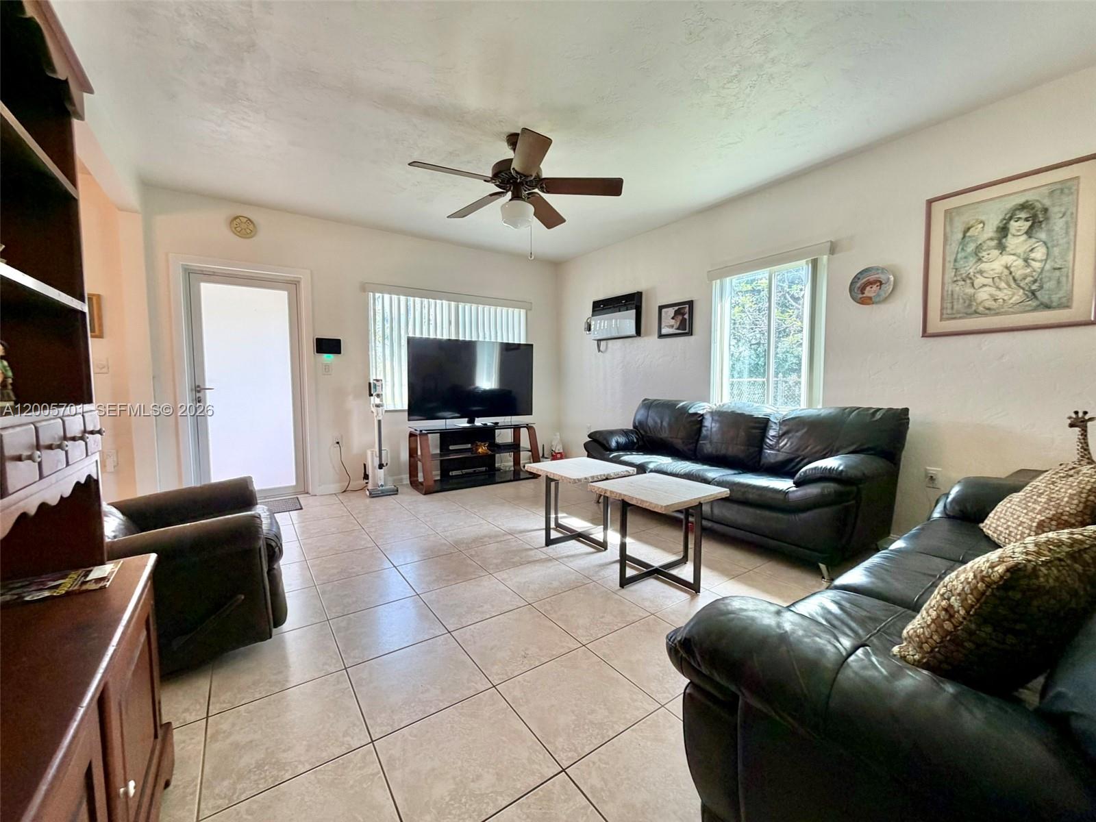 A living room features tile floors, leather sofas, a ceiling fan, and a television — 1698 NE 177th St, North Miami Beach FL 33162, NORTH MIAMI BEACH, FL