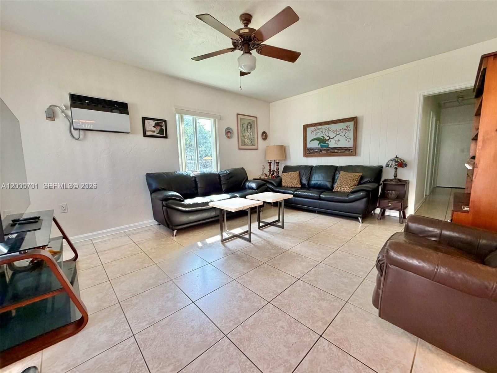 A living room features tiled floors, two black leather sofas, and a ceiling fan — 1698 NE 177th St, North Miami Beach FL 33162, NORTH MIAMI BEACH, FL