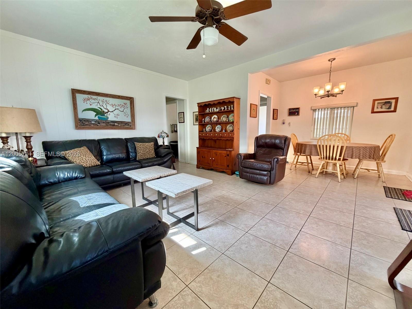 A living room with tiled floors, a black leather sofa, and an adjacent dining area — 1698 NE 177th St, North Miami Beach FL 33162, NORTH MIAMI BEACH, FL