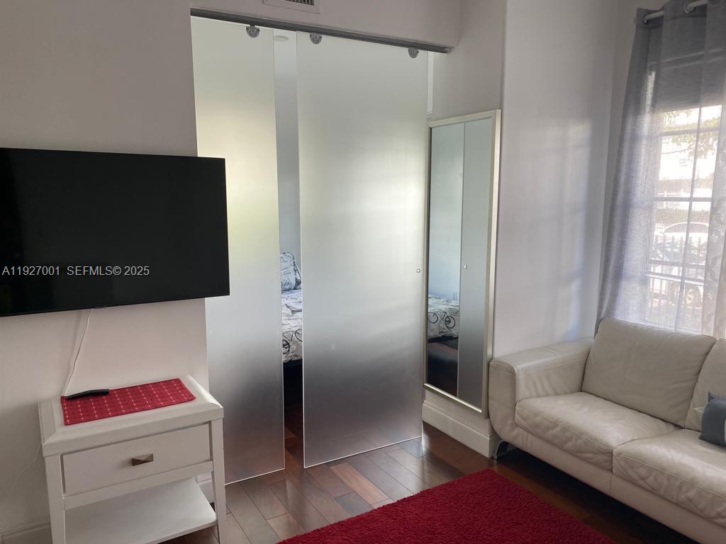 A living room features a white sofa, a television, and frosted glass sliding doors — 526 15 ST # 2, Miami Beach FL 33139, MIAMI BEACH, FL