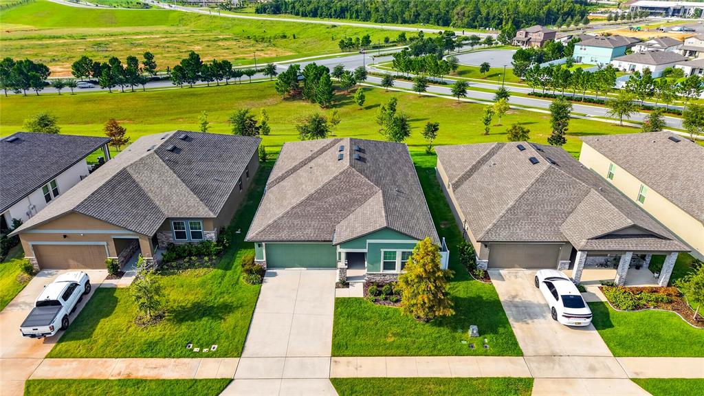 An aerial view shows three suburban houses with driveways and lawns in a residential neighborhood — 1785 SUNDANCE CHASE ROAD, MINNEOLA, FL