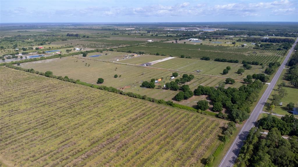 An aerial view shows a large, flat rural property with fields, trees, and a road — 11525 138TH AVENUE, FELLSMERE, FL