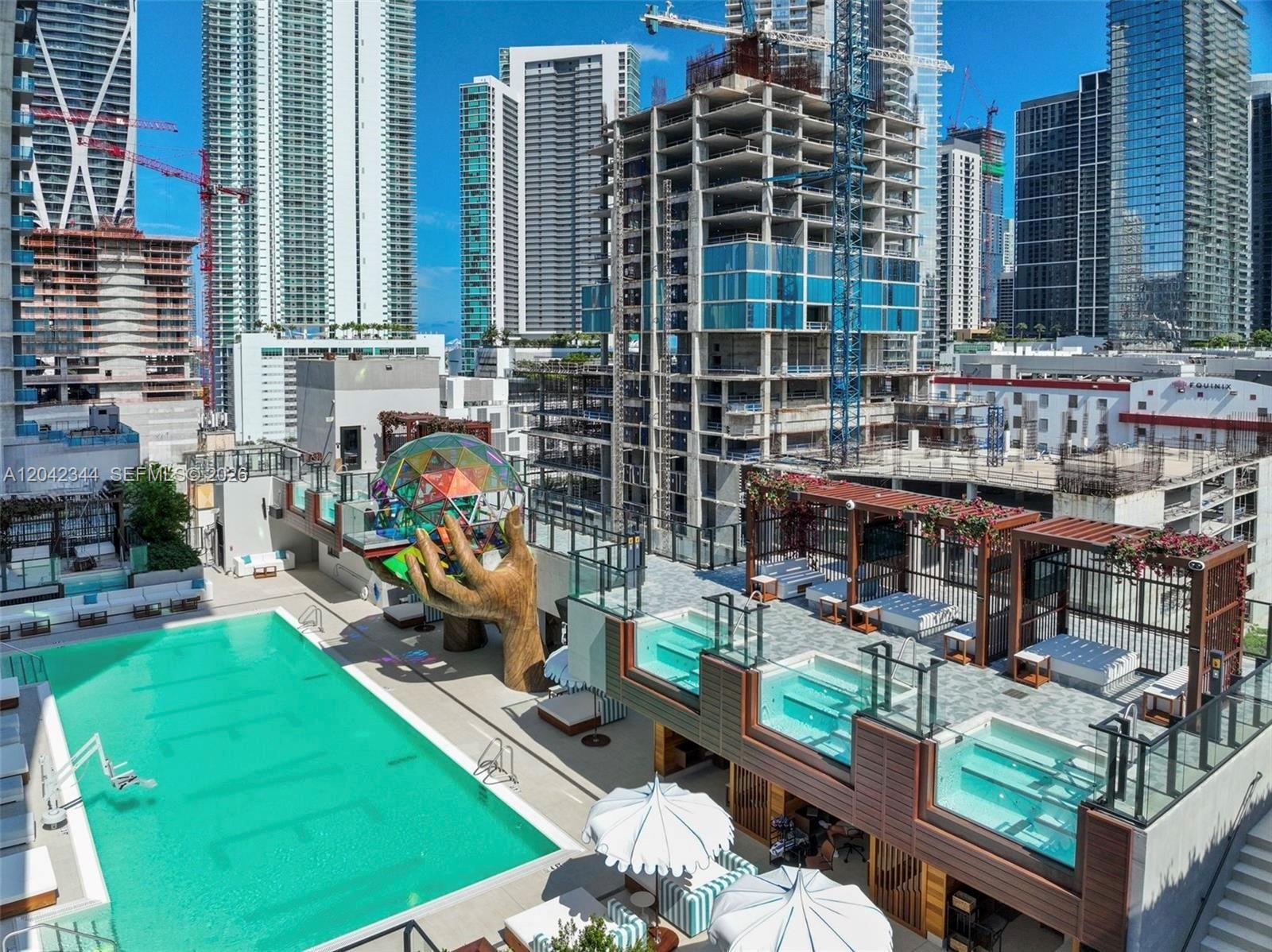 An elevated outdoor pool deck features a large sculpture of a hand holding a glass sphere — 20 NE 11th st # 4604, Miami FL 33132, MIAMI, FL