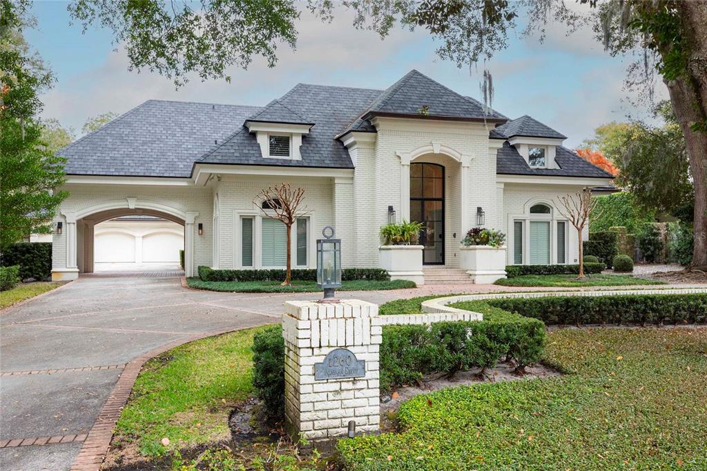 A white brick house with a dark shingled roof and a covered driveway entrance — 1260 ALABAMA DRIVE, WINTER PARK, FL