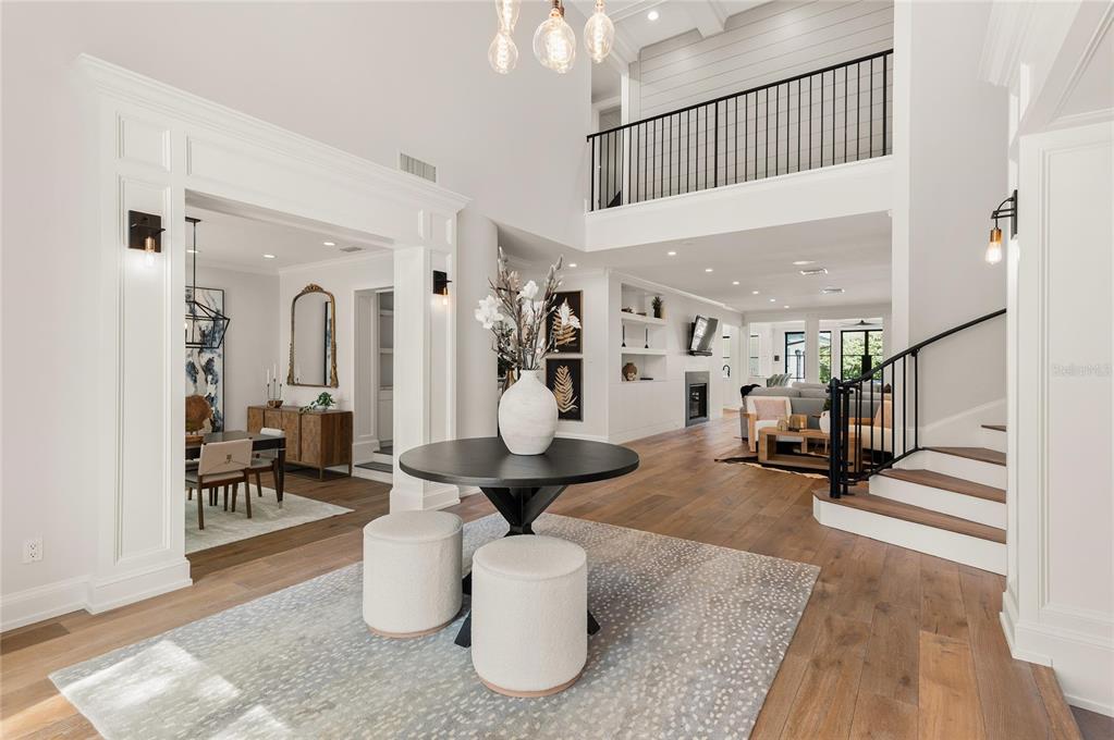 A bright, two-story foyer features a round table, two ottomans, and a staircase with railing — 1260 ALABAMA DRIVE, WINTER PARK, FL