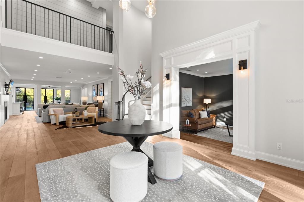 A bright foyer features a round table, two ottomans, and an arched entryway to a den — 1260 ALABAMA DRIVE, WINTER PARK, FL