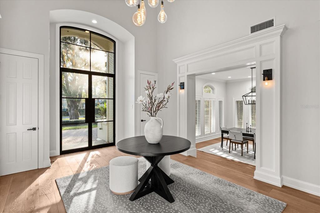 A bright foyer features a black round table, a patterned rug, and a large arched window — 1260 ALABAMA DRIVE, WINTER PARK, FL