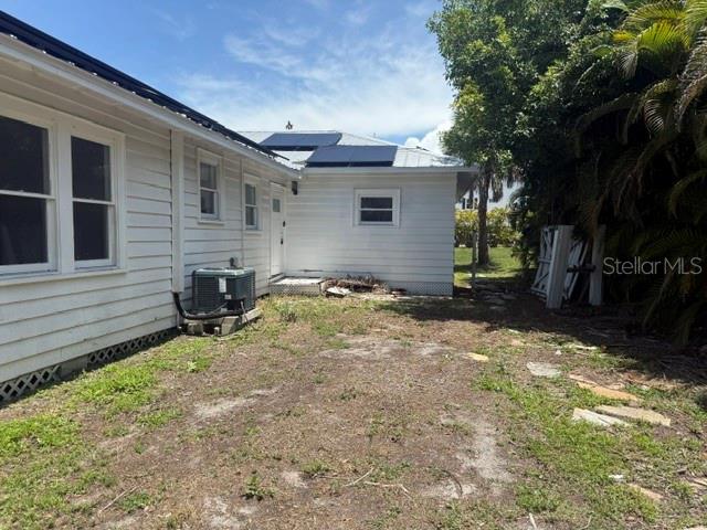 The exterior of a white, single-story house with a metal roof and an air conditioning unit — 617 SIESTA DRIVE, SARASOTA, FL