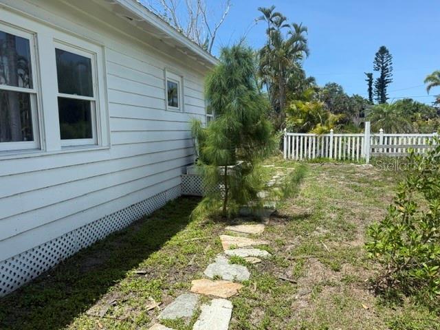 The exterior of a white house features horizontal siding, a lattice foundation, and a stone path — 617 SIESTA DRIVE, SARASOTA, FL