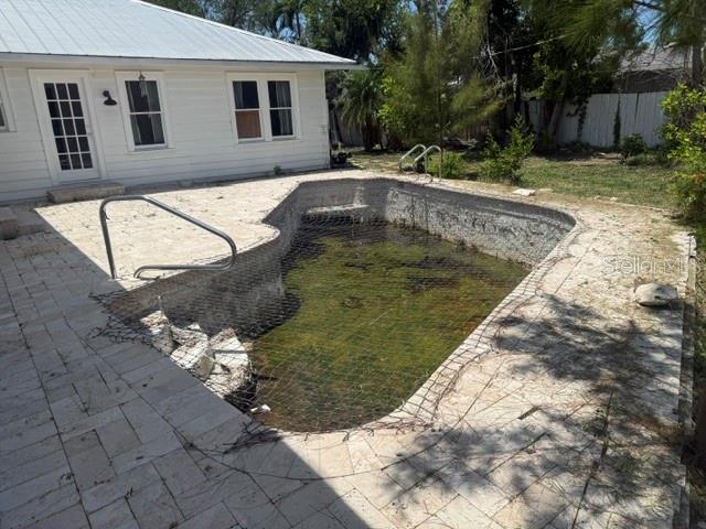 A backyard features a white house with a pool covered by a safety net — 617 SIESTA DRIVE, SARASOTA, FL