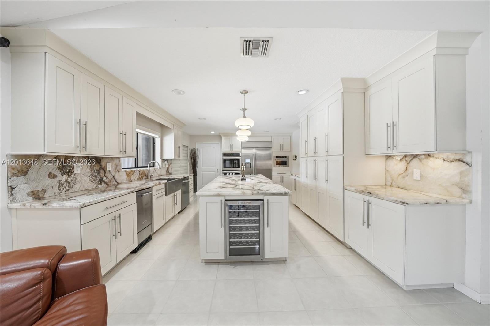 A modern kitchen features white cabinetry, marble countertops, a central island, and stainless steel appliances — 15130 SW 164th Ter, Miami FL 33187, MIAMI, FL