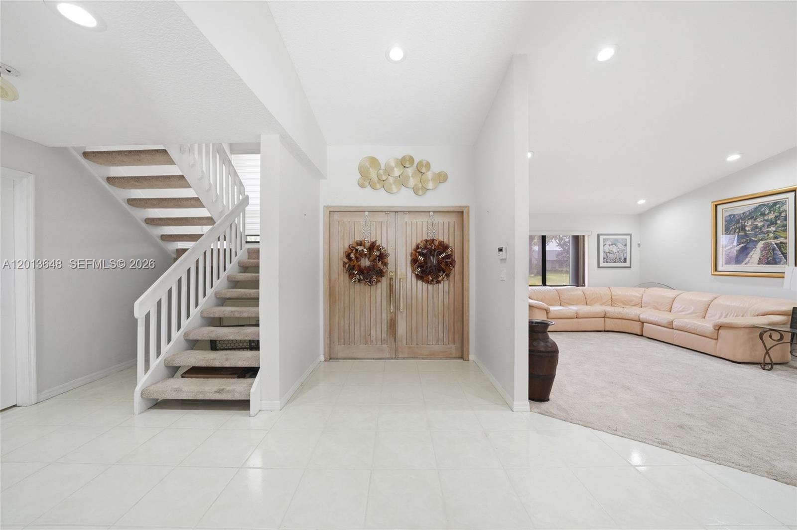 A foyer with white tile floors, a staircase, and a doorway leading to a living room — 15130 SW 164th Ter, Miami FL 33187, MIAMI, FL
