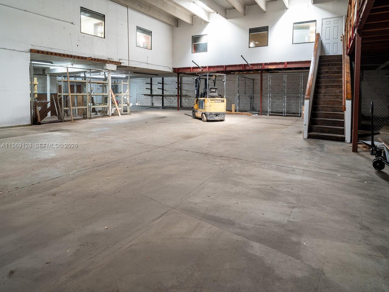 An industrial warehouse space features a concrete floor, a forklift, and a wooden staircase — 7801 W 25th Ct, Hialeah FL 33016, HIALEAH, FL