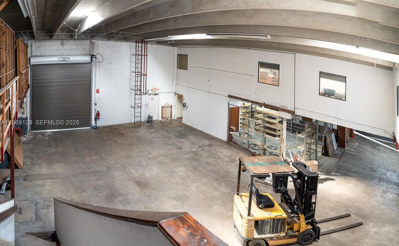 An industrial warehouse space features a concrete floor, a roll-up door, and a yellow forklift — 7801 W 25th Ct, Hialeah FL 33016, HIALEAH, FL