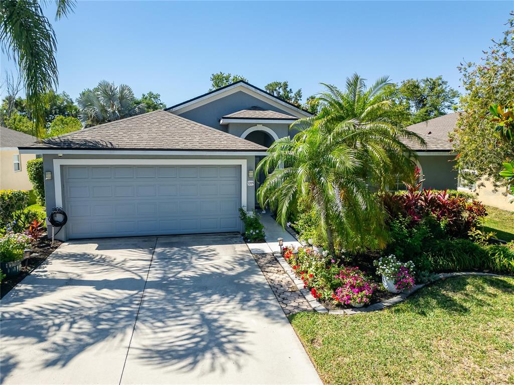 A single-story house with a gray garage, a palm tree, and a landscaped front yard — 5209 LANSDOWNE WAY, PALMETTO, FL