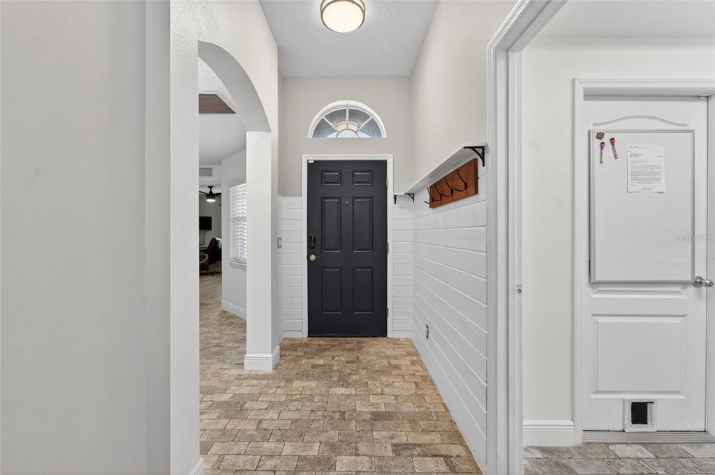 An entryway features a black front door, white shiplap walls, and light-colored stone flooring — 5209 LANSDOWNE WAY, PALMETTO, FL