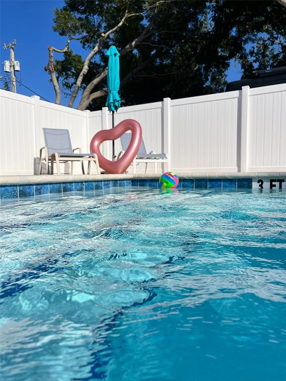 A swimming pool with a heart-shaped float, a beach ball, and chairs against a white fence — 1901 HYDE PARK STREET UNIT C, SARASOTA, FL