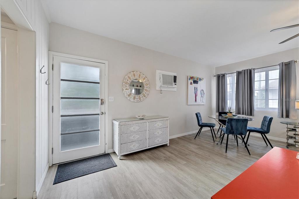 A dining area with a white dresser, a glass table, and blue chairs near a door — 1901 HYDE PARK STREET UNIT C, SARASOTA, FL