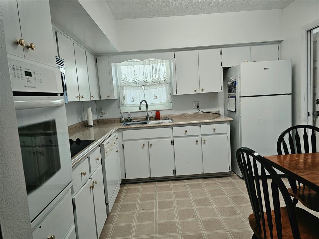 A kitchen with white cabinets, white appliances, a double sink, and a checkered floor — 2292 COSTA RICAN DRIVE UNIT 24, CLEARWATER, FL