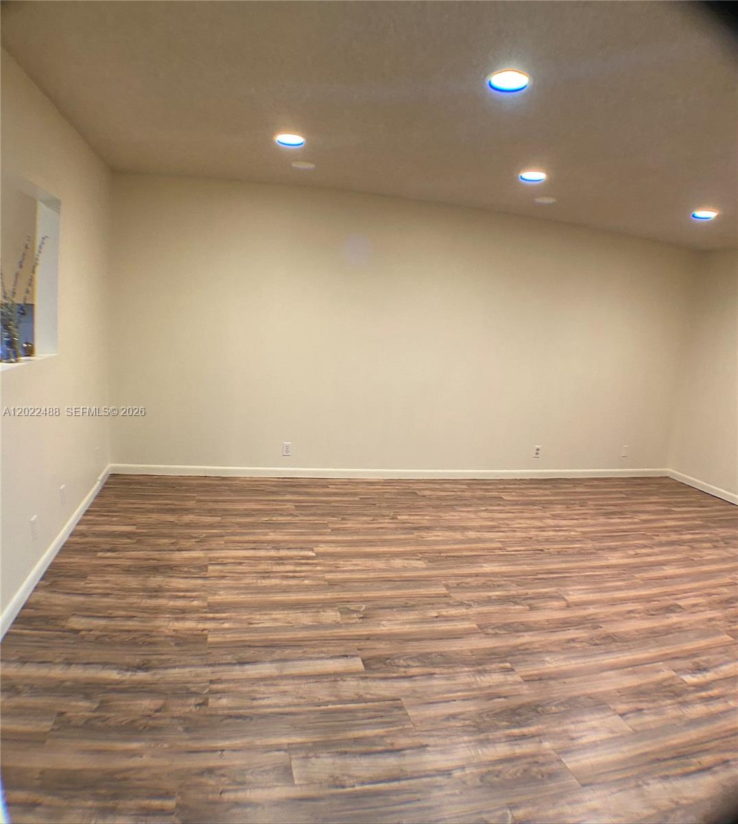 An empty room features light-colored walls, recessed ceiling lights, and wood-look laminate flooring — 2061 NW 47th Ter # 302, Lauderhill FL 33313, LAUDERHILL, FL