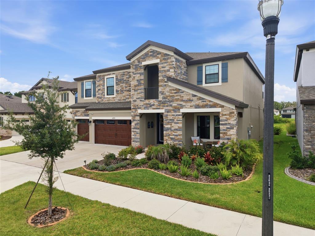 A two-story house with a stone facade, brown garage doors, and a landscaped front yard — 12970 STEED TRACE LOOP, LITHIA, FL