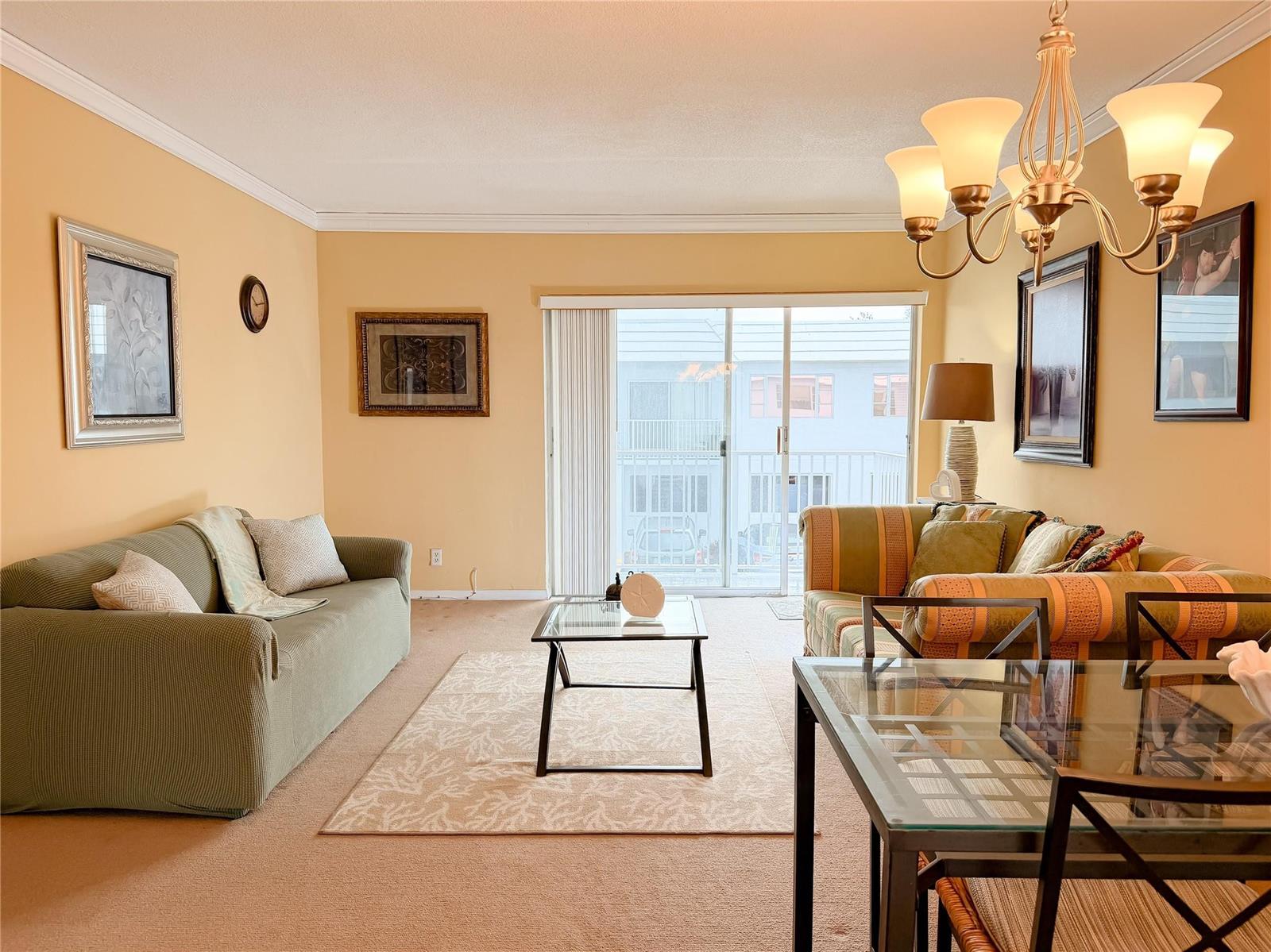 A living room with beige walls, a green sofa, a glass coffee table, and dining area — 412 S Cypress Road # 225, Pompano Beach FL 33060, POMPANO BEACH, FL