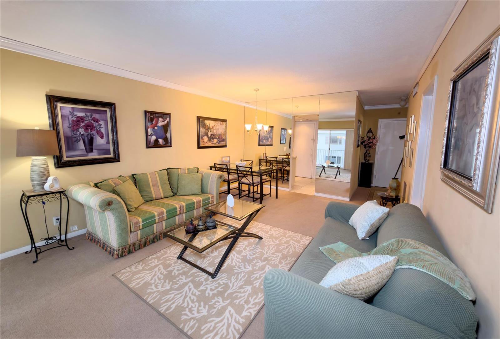 A living room features two sofas, a glass coffee table, and a mirrored dining area wall — 412 S Cypress Road # 225, Pompano Beach FL 33060, POMPANO BEACH, FL