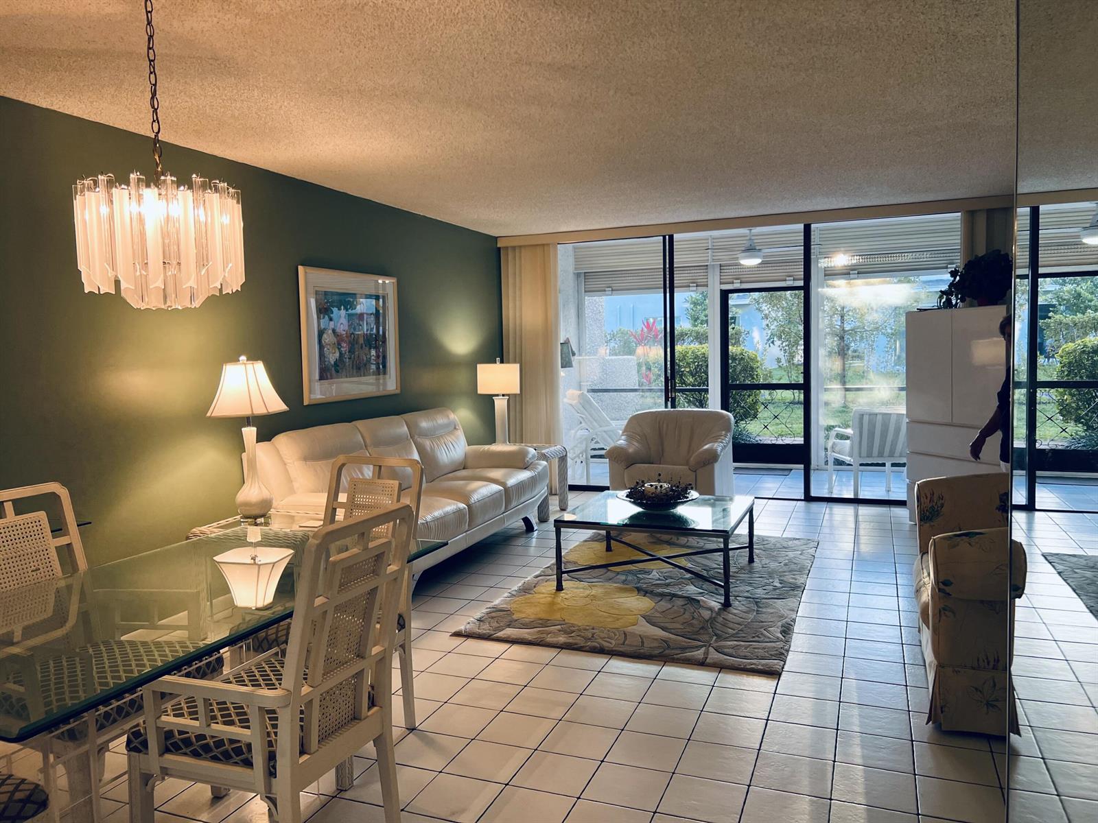 A living and dining area with white tile floors, a green wall, and glass sliding doors — 4387 Trevi Court, FL 33467, FL