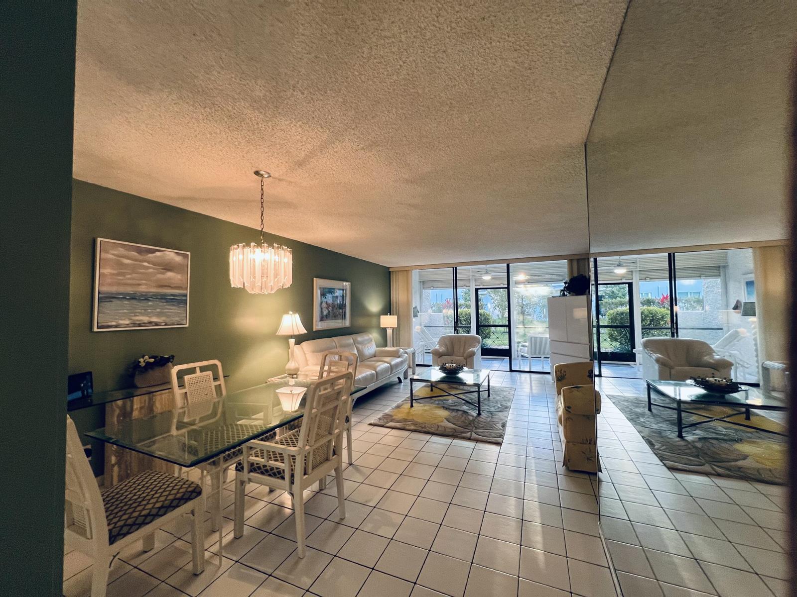 A living and dining room with tiled floors, a green accent wall, and mirrored walls — 4387 Trevi Court, FL 33467, FL
