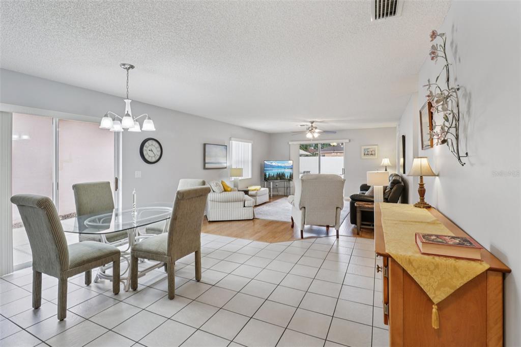 A dining area with tile flooring transitions into a carpeted living room with neutral furniture — 914 MENDOZA BOULEVARD, LADY LAKE, FL
