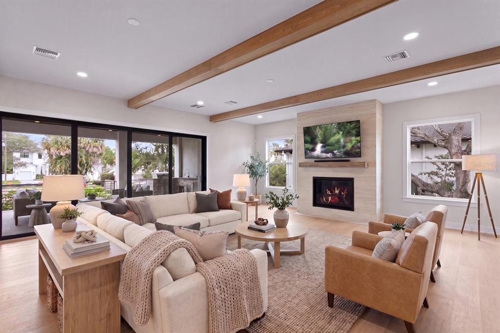 A living room features a stone fireplace, wood ceiling beams, and sliding glass patio doors — 5021 W LEONA STREET, TAMPA, FL