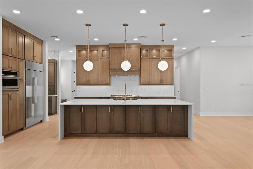 A modern kitchen features wood cabinets, a white quartz island, and three globe pendant lights — 5021 W LEONA STREET, TAMPA, FL
